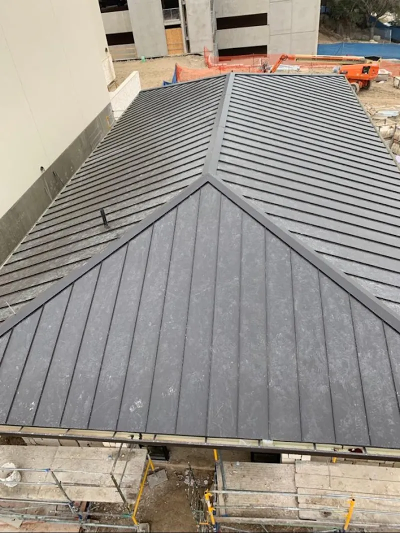 Commercial metal roof construction with crane equipment in Rayne